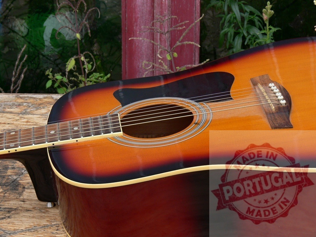 Acoustic guitar resting on wooden table outdoors | Sunburst finish acoustic guitar resting on a wooden table outdoors, ready to be played - Realisiert mit Pictrs.com