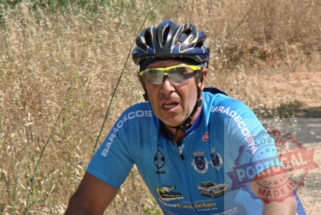 Cyclist wearing helmet and glasses is cycling on a country road | Male cyclist wearing a blue shirt and cycling on a country road - Realisiert mit Pictrs.com