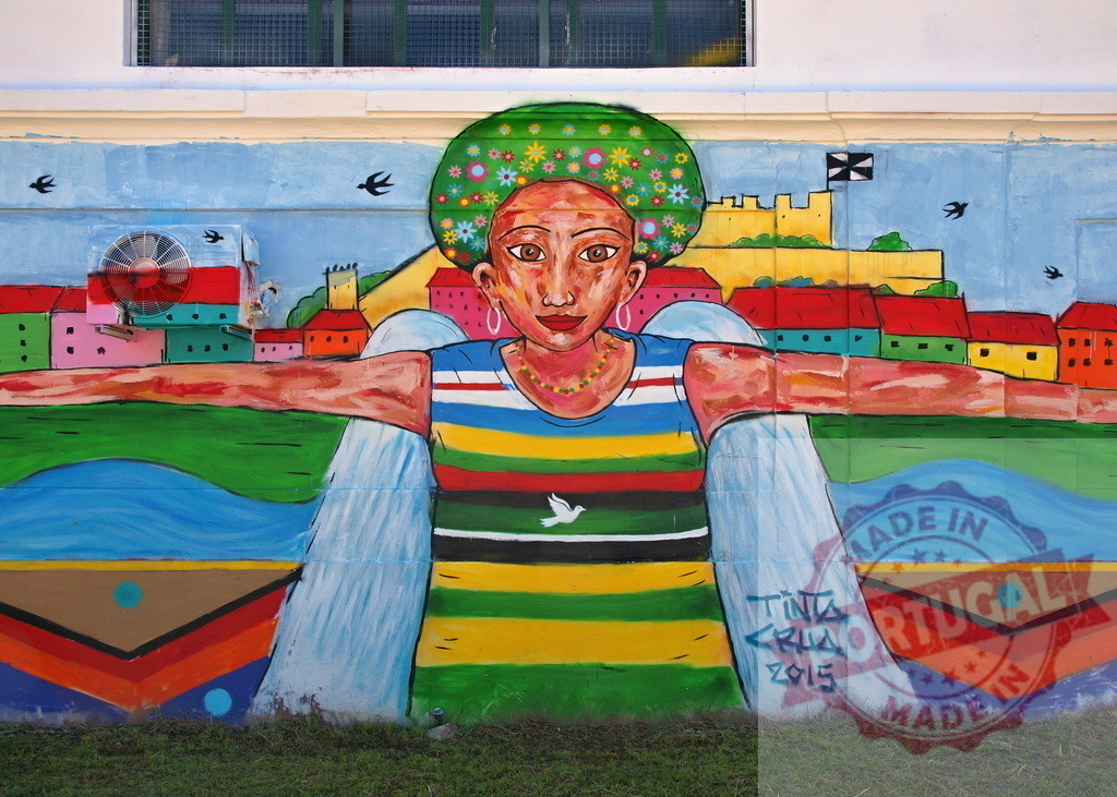 Colorful mural depicting woman embracing a stylized cityscape with open arms | Vibrant street art showcasing a female figure embracing a cityscape, symbolizing community and inclusion - Realisiert mit Pictrs.com