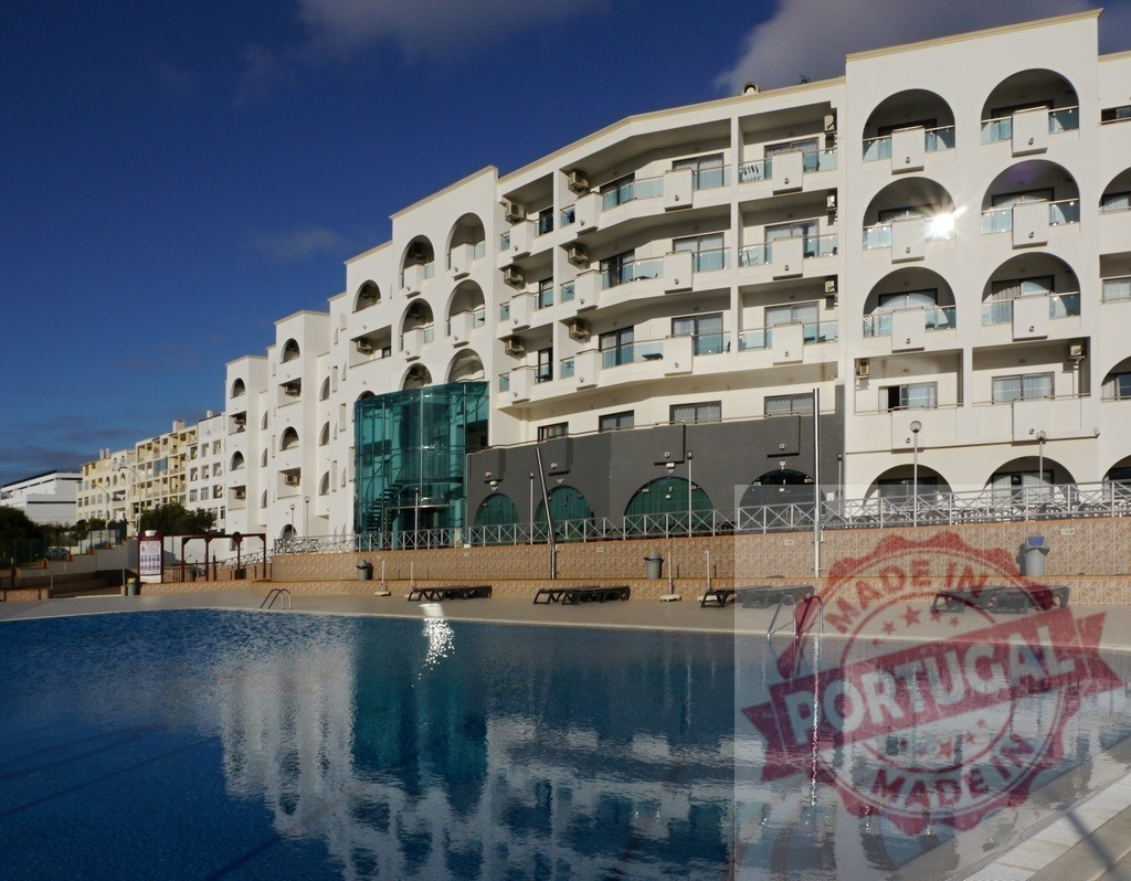Modern resort hotel building reflecting in swimming pool | Resort white building reflecting in blue swimming pool water under clear sky - Realisiert mit Pictrs.com