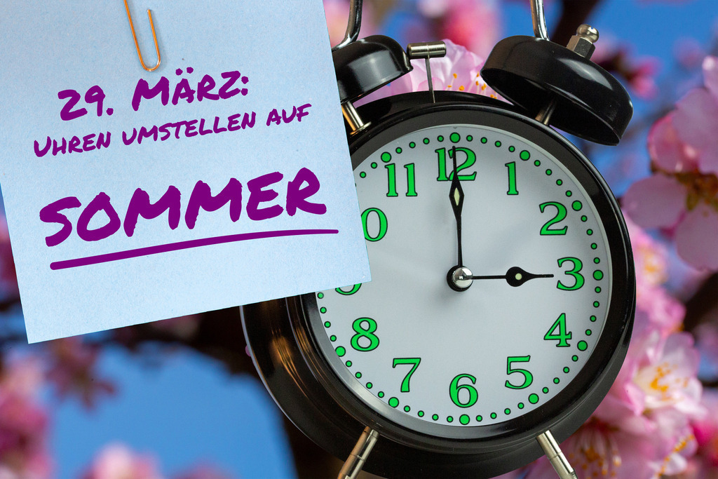 Zeitumstellung Sommerzeit 2026: Wecker und Notizzettel als Erinnerung zur Zeitumstellung | (Fotomontage) Zeitumstellung Sommerzeit Symbolbild: Wecker vor Mandelblüte und Text 29. MÄRZ UHREN UMSTELLEN AUF SOMMER - Realisiert mit Pictrs.com