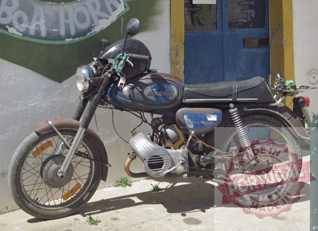 Old rusty Macal motorcycle parked near a wall | Vintage and rusty Macal motorcycle parked near a white and yellow wall with a blue door and graffiti - Realisiert mit Pictrs.com