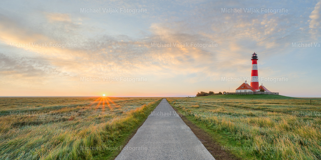 Leuchtturm Westerhever bei Sonnenaufgang | Der Leuchtturm Westerhever ist eines der bekanntesten Wahrzeichen an der Nordseeküste. Er steht auf einer Warft, die von zwei Salzwiesen umgeben ist. Bei Sonnenaufgang bietet er einen malerischen Anblick, wenn die ersten Sonnenstrahlen seine roten und weißen Streifen zum Leuchten bringen. Der Leuchtturm ist seit 1908 in Betrieb und dient der Orientierung für die Schifffahrt in der Eiderstedter Bucht. - Realisiert mit Pictrs.com