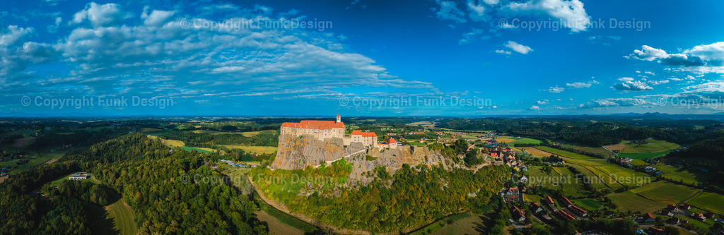 Drohnenpanorama der Riegersburg – Steiermark, Österreich | Die Riegersburg thront majestätisch auf ihrem markanten Felsen und blickt weit über das steirische Hügelland. Aus der Drohnenperspektive wirkt die Anlage besonders eindrucksvoll, eingerahmt von Feldern, Wäldern und einem dramatischen Himmel.