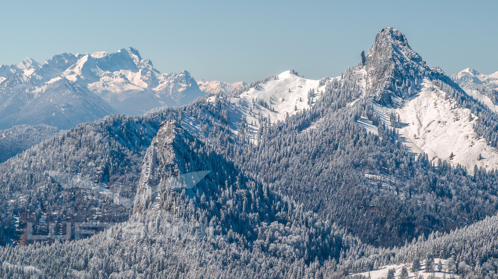 Leonhardstein, Ross-/Buchstein und die Zugspitze; W39 | Ein eindrucksvoller Blick auf Leonhardstein, Ross und Buchstein, dahinter die majestätische Zugspitze: Die schneebedeckten Gipfel heben sich klar vor dem Himmel ab und zeigen die ganze Vielfalt der bayerischen Alpen. Die winterliche Ruhe legt sich über die Landschaft und verleiht diesem Panorama eine besondere Klarheit und Tiefe – ein Moment, der die Kraft und Schönheit der Region rund um den Tegernsee spürbar macht. - Realisiert mit Pictrs.com