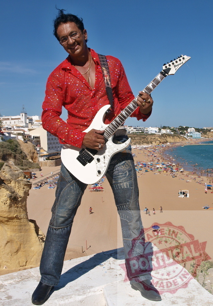 Musician playing electric guitar in Algarve, Portugal | Guitarist playing a white electric guitar on a viewpoint in Algarve, Portugal, with Praia da Rocha beach in the background - Realized with Pictrs.com