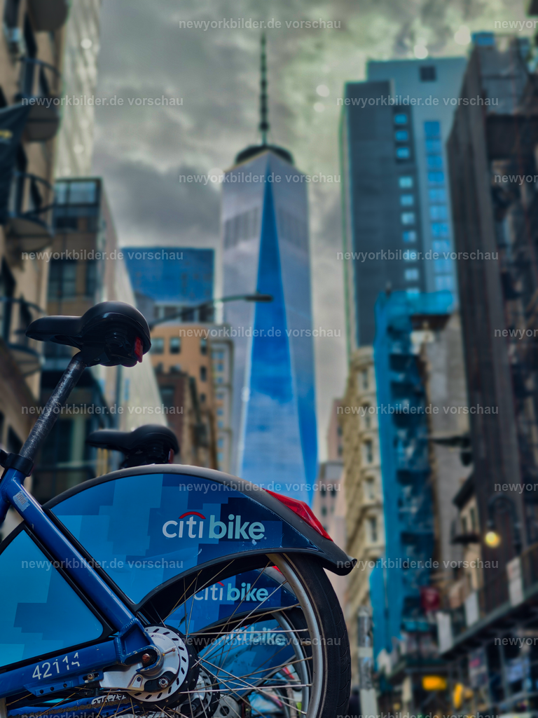 Citibikes & One World Trade Center – Gigantische Perspektive aus Manhattan | Dieses Bild vereint zwei Symbole von New York City: die Citibikes, die überall in der Stadt zu finden sind, und das majestätische One World Trade Center. Aus der Bodenperspektive fotografiert, entsteht eine beeindruckende Komposition, die die Größenverhältnisse der Metropole sichtbar macht. Die Fahrräder im Vordergrund stehen für Mobilität, Freiheit und den urbanen Lifestyle, während der Wolkenkratzer im Hintergrund die Kraft und Vision der Stadt verkörpert. Die Linienführung zieht den Blick nach oben, vorbei an den Details der Bikes bis in den Himmel, wo das One World Trade Center in seiner ganzen Eleganz erstrahlt. Die Szene ist dynamisch und modern, ein perfektes Zusammenspiel von Architektur und Alltag.