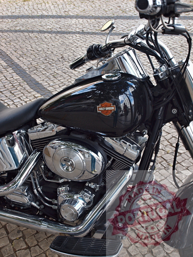 Harley-Davidson motorcycle engine and fuel tank | Black Harley-Davidson motorcycle parked on cobblestone street showcasing classic design - Realized with Pictrs.com