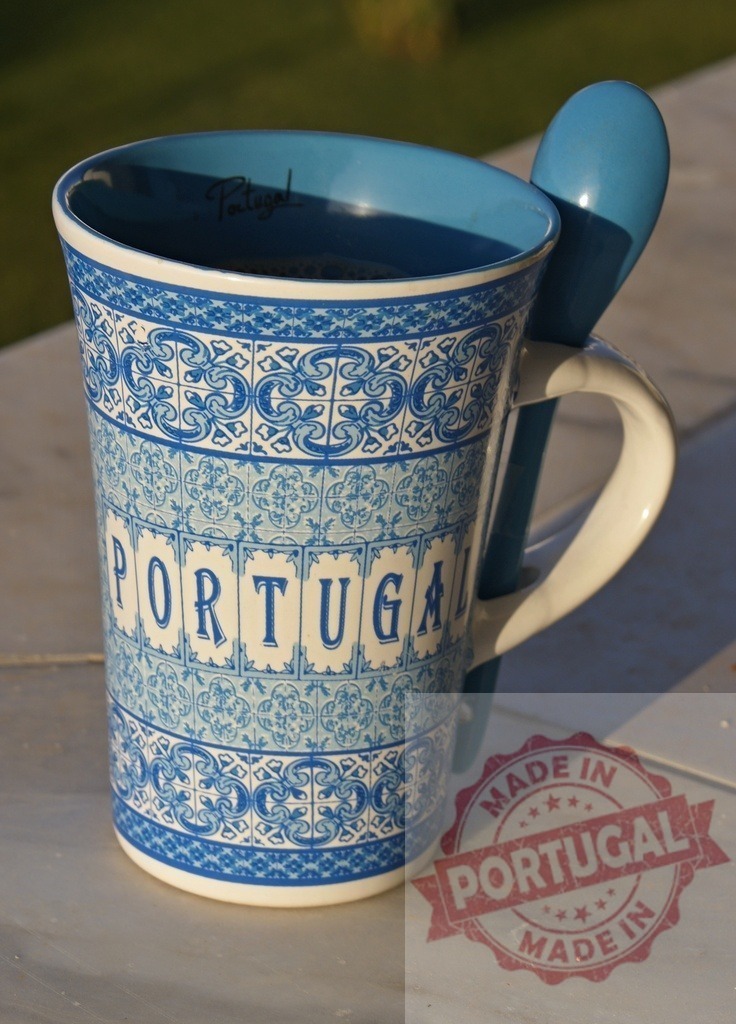 Portugal souvenir mug with azulejos pattern and spoon | Ceramic mug with Portugal text and blue azulejo design, holding a blue spoon - Realized with Pictrs.com