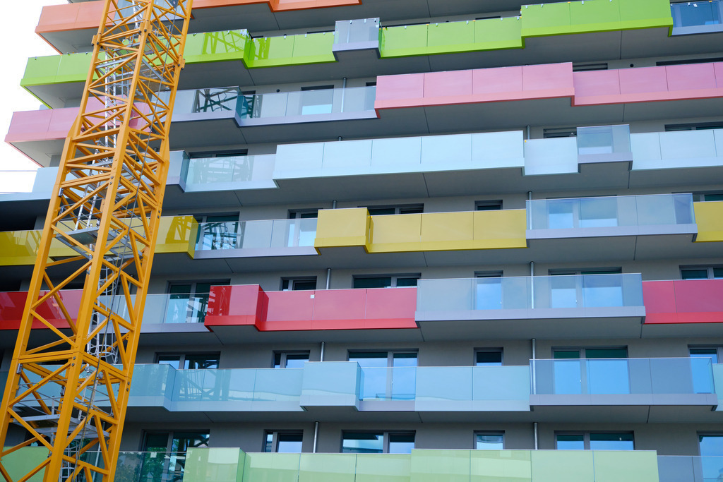 Vorderansicht Neubau mit bunten Balkonen | Wien, Austria - August 20, 2024: Vorderansicht einer Neubau-Wohnung mit bunten Balkonen und Hochkran. - Realisiert mit Pictrs.com
