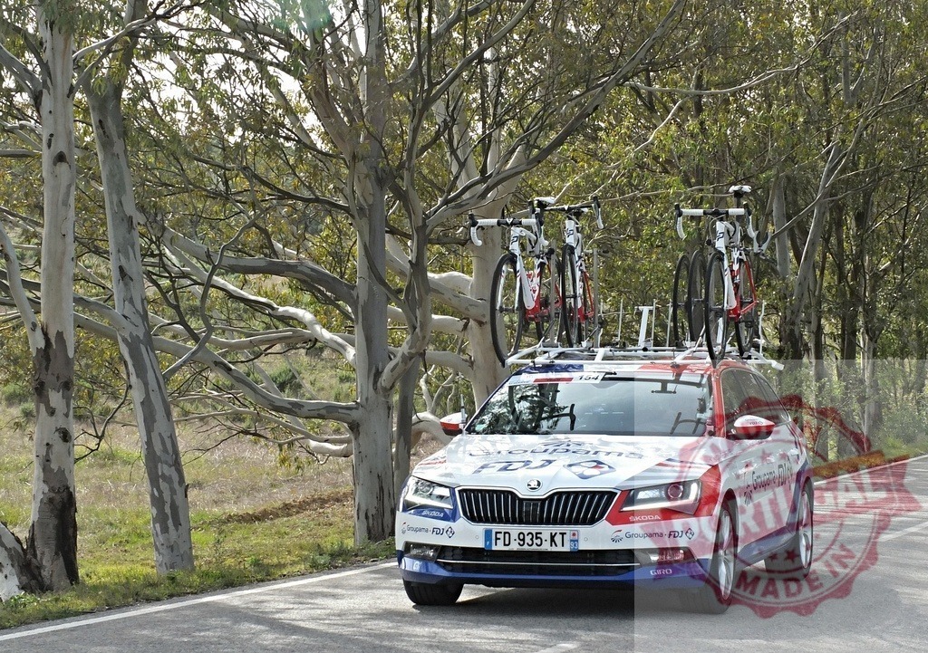 Groupama-FDJ cycling team car carrying racing bicycles | Groupama-FDJ cycling team support car driving on a road among eucalyptus trees - Realized with Pictrs.com