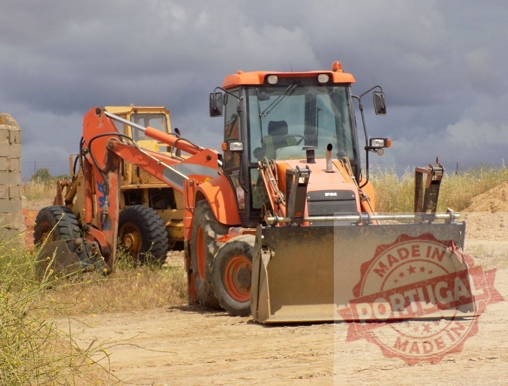 Orange backhoe loader parked on dirt road | Backhoe loader and yellow excavator resting at a construction site - Realized with Pictrs.com