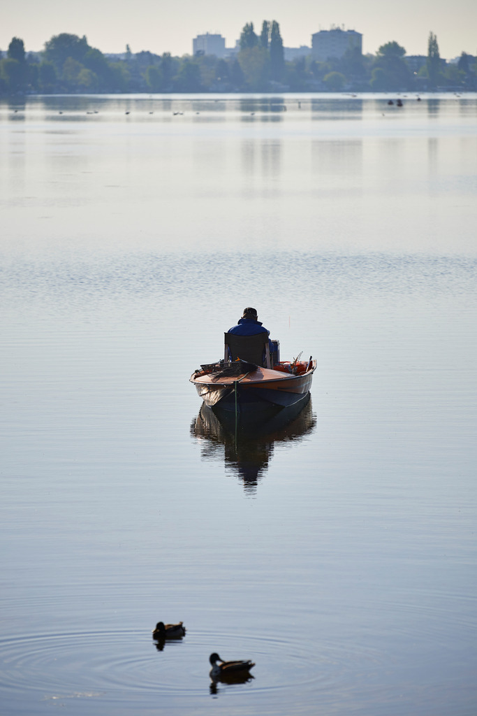 Fischer im Boot sitzend | Wien, Austria - April 22, 2016: Fischer im Boot sitzend, im Hintergrund Hochhaeuser. - Realisiert mit Pictrs.com