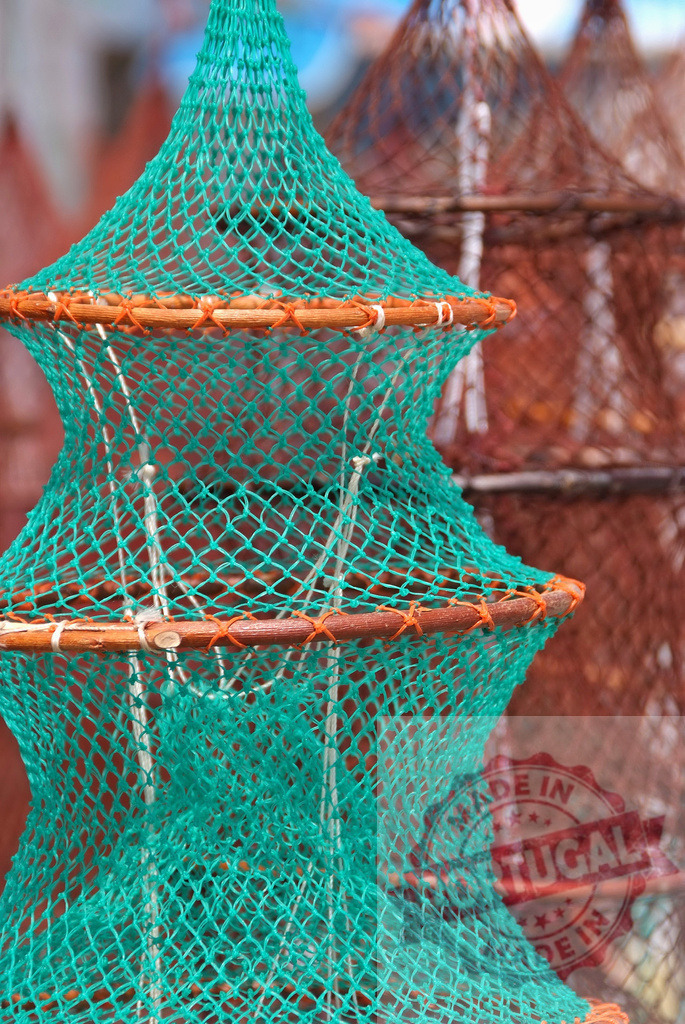 Green fishing trap for crab and lobster | Close up view of a green fishing trap with other traps in the background - Realisiert mit Pictrs.com