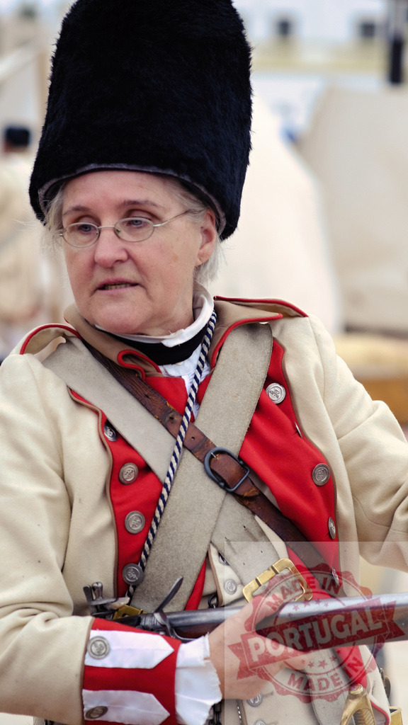 Woman portraying Revolutionary War era soldier holding musket | Mature woman participating in a historical reenactment as a period soldier - Realized with Pictrs.com