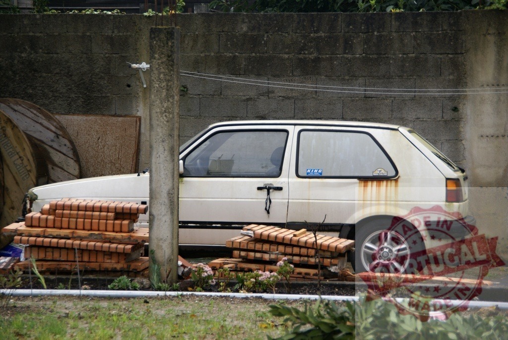 Abandoned white Volkswagen Golf hatchback decaying outdoors | White Volkswagen Golf hatchback showing rust and decay with construction bricks in a junkyard - Realisiert mit Pictrs.com