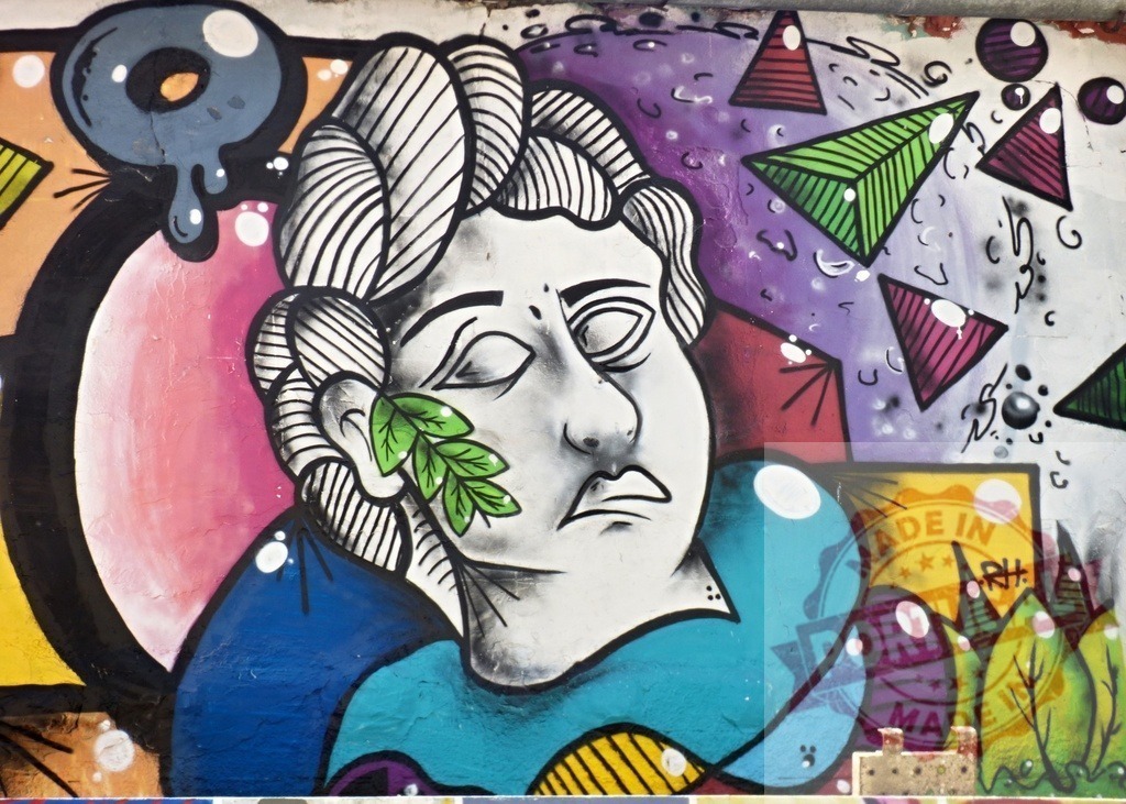 Classical statue head graffiti and colorful street art mural | Artistic street art mural displaying a classical statue head with a leaf and abstract geometric shapes - Realisiert mit Pictrs.com