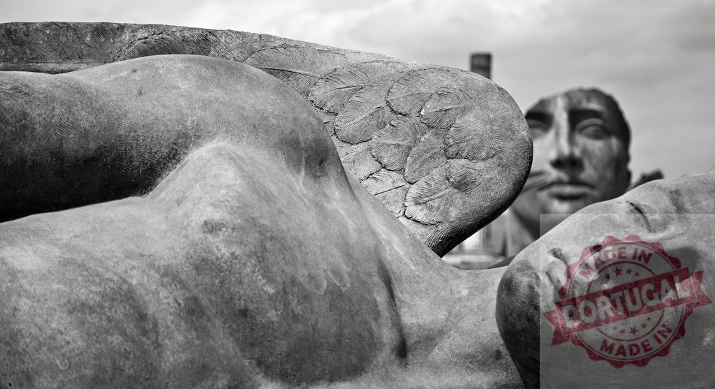 Angel and sleeping figure with abstract face in background | Stone statues depicting symbolic figures and a winged angel - Realisiert mit Pictrs.com