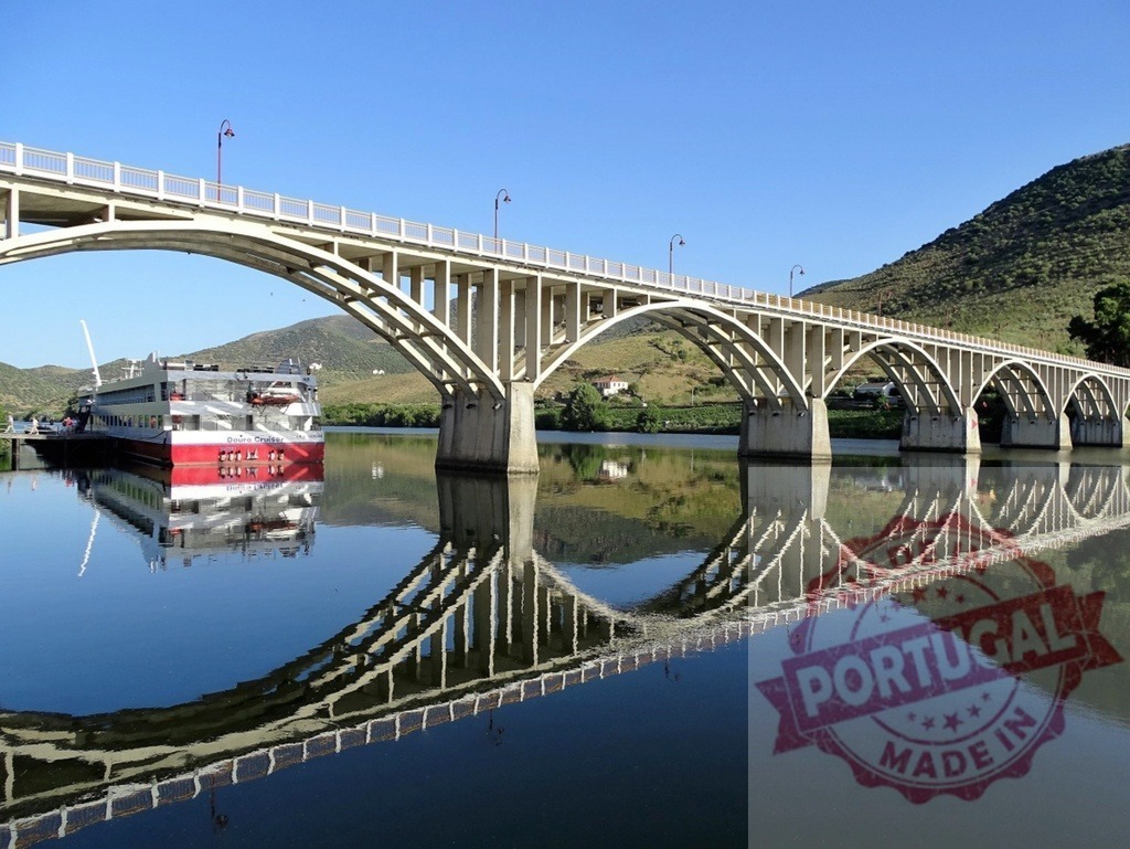 Arched bridge reflecting on Douro River with boat | Bridge and boat reflecting on calm Douro River waters under a clear sky - Realized with Pictrs.com