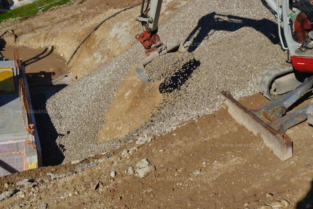 Drainage Kies | Bagger beim Verfüllen der Baugrube mit kapillarbrechendem Kies