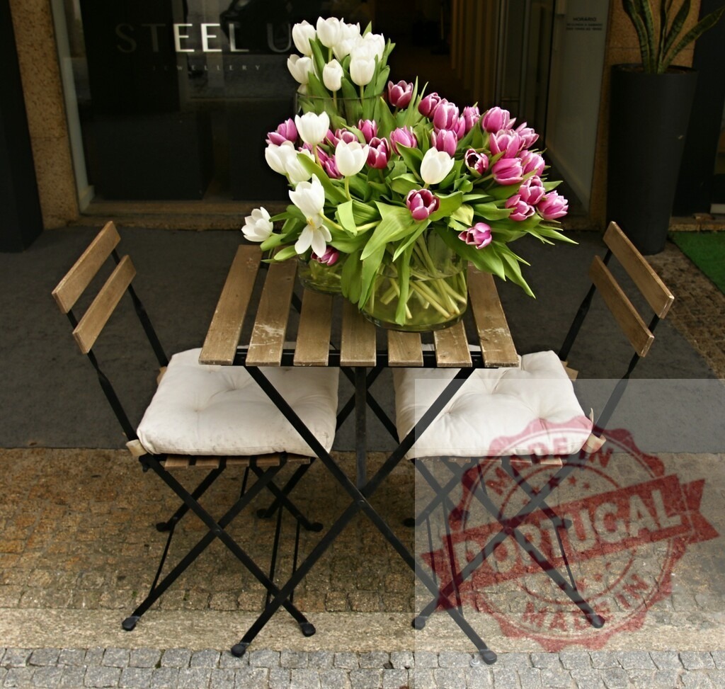 Bistro table with tulip bouquets setting up for spring | Bistro table having two large bouquets of white and purple tulips, set up on a sidewalk - Realisiert mit Pictrs.com