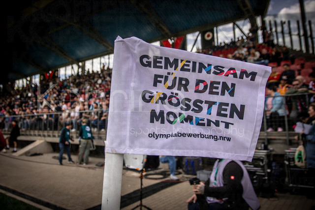 Viktoria Koeln vs. SV Wehen Wiesbaden, 11.04.2026 | KOELN, GERMANY - APRIL 11, 2026:  A corner flag with an advertisement for the region's Olympic bid before the 3rd division match between Viktoria Koeln vs. SV Wehen Wiesbaden at the Sportpark Hoehenberg on matchday 7 on April 11, 2026 in Koeln, Germany. DFL REGULATIONS PROHIBIT ANY USE OF PHOTOGRAPHS AS IMAGE SEQUENCES AND/OR QUASI-VIDEO.
