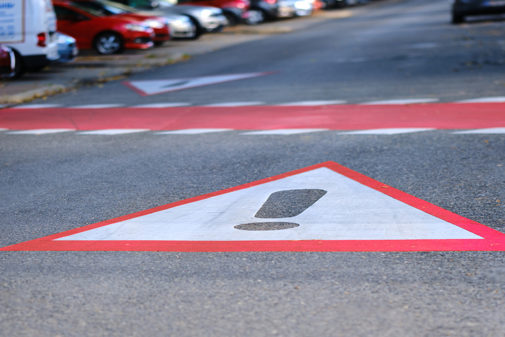 Achtung Verkehrsschild auf der Strasse | Wien, Austria - November 06, 2023: Achtung Verkehrsschild vor einem Fussweg auf der Strasse, im Hintergrund parkende Autos. - Realisiert mit Pictrs.com