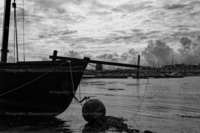 Bootssilhouette am Hafen | Schwarzweißaufnahme eines alten Boots im Hafen mit dunkler Silhouette, Wasser und dramatischem Himmel. Die ruhige Stimmung, die reduzierte Bildsprache und die maritime Szene verleihen dem Motiv einen zeitlosen, dokumentarischen Charakter. - Realisiert mit Pictrs.com