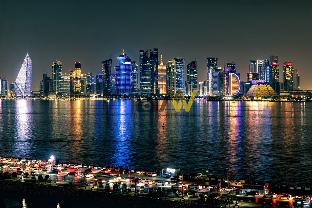 Strahlende Skyline von Doha------Lichterglanz auf dem Meer | Das Bild zeigt die beleuchtete Skyline von Doha, Katar, bei Nacht, aufgenommen von der Doha Corniche. Die Doha Corniche ist eine sieben Kilometer lange Uferpromenade entlang der halbmondförmigen Bucht von Doha. Sie verbindet das moderne Geschäftsviertel Al Dafna im Norden mit den historischen Teilen der Altstadt Dohas im Süden. Die Gegend ist bekannt für ihre zahlreichen Wolkenkratzer, Luxushotels, Parks und das Museum für Islamische Kunst.  - Realisiert mit Pictrs.com