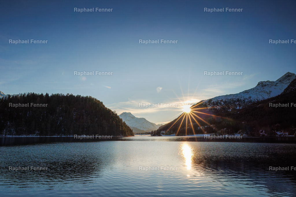 Sonnenuntergang am Champfèrersee | Ein ruhiger Abend am Lej da Champfèr im Engadin: Die Sonne sinkt hinter die majestätischen Berggipfel und taucht den Himmel in leuchtende Orange- und Rosatöne. Das Wasser des Sees reflektiert die Farben des Sonnenuntergangs und verleiht der Landschaft eine besondere Magie. In der Stille des Moments verschmelzen Himmel und Erde zu einem harmonischen Bild, das die Schönheit der Engadiner Natur perfekt widerspiegelt.