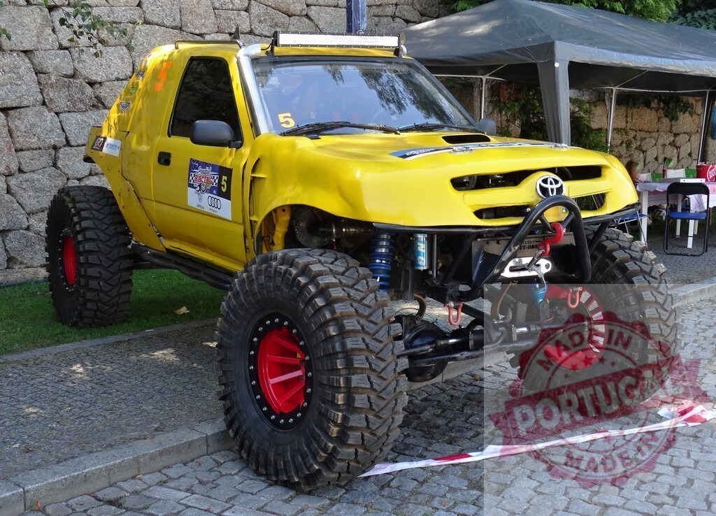 Yellow tuned Toyota off-road vehicle showing its big wheels | Powerful tuned Toyota truck parked on a cobblestone square, ready for an off-road adventure - Realisiert mit Pictrs.com