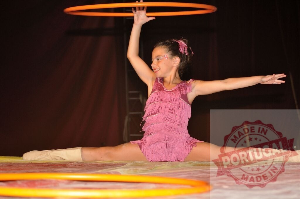 Young girl performing splits with hula hoops | Young girl doing the splits on stage, holding a hula hoop during a performance - Realized with Pictrs.com