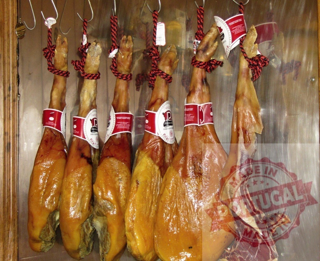 Jamon serrano hams hanging in butcher shop | Cured ham legs hanging from hooks in a traditional Spanish butcher shop - Realisiert mit Pictrs.com