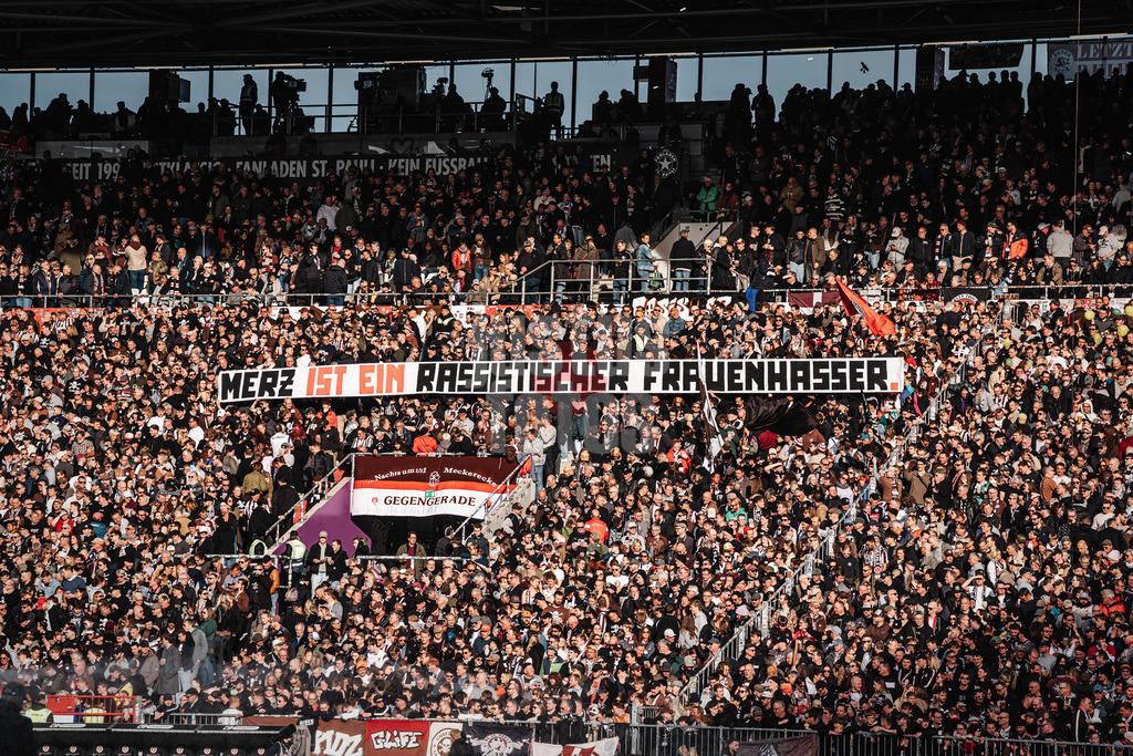 Fußball | Männer | Saison 2025/2026  | Fußball-Bundesliga | 29. Spieltag | FC St. Pauli vs. FC Bayern München | 11.04.2026 | Fans des FC St. Pauli halten ein Banner Transparent Spruchband Merz ist ein rassistischer Frauenhasser Friedrich Merz Bundeskanzler