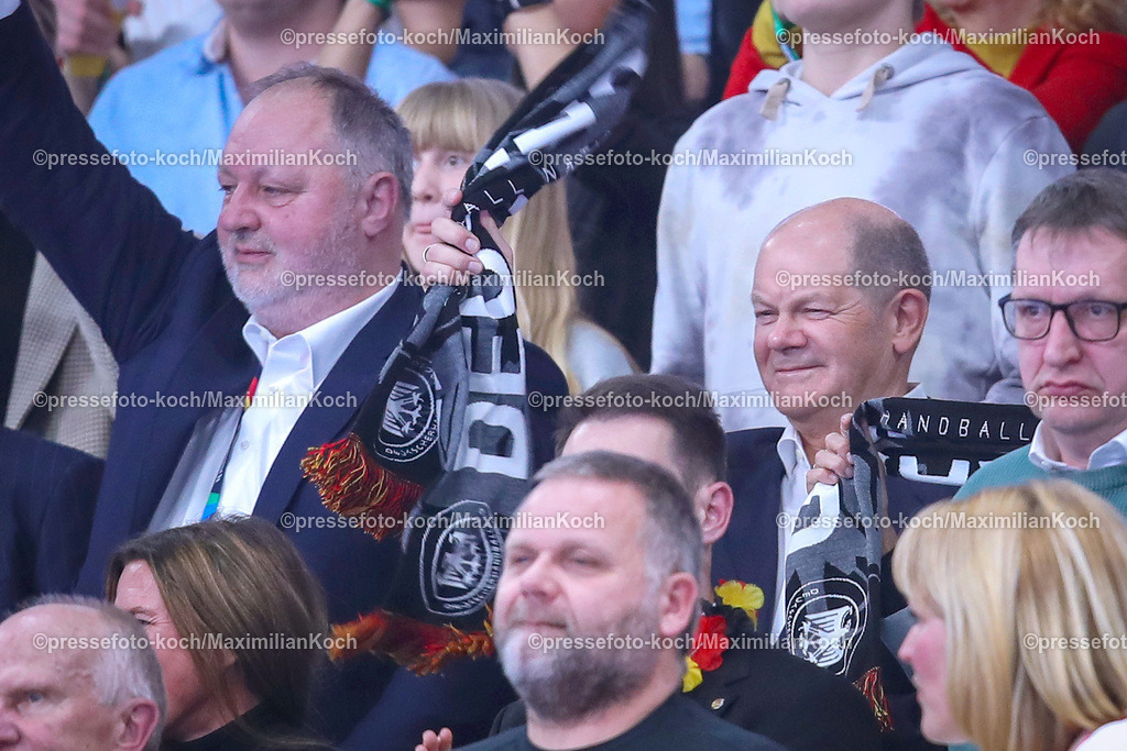 EHFEURO14012402127 | 14.01.2024, EHF EURO 2024, Männer Europameisterschaft Handball, Mercedes-Benz-Arena in Berlin, Deutschland - Nordmazedonien: DHB Präsident Andreas Michelmann und Bundeskanzler Olaf Scholz sitzen auf der Tribüne und feuern die Mannschaft an. Kanzler Scholz schwenkt einen Fanschal in der Hand,