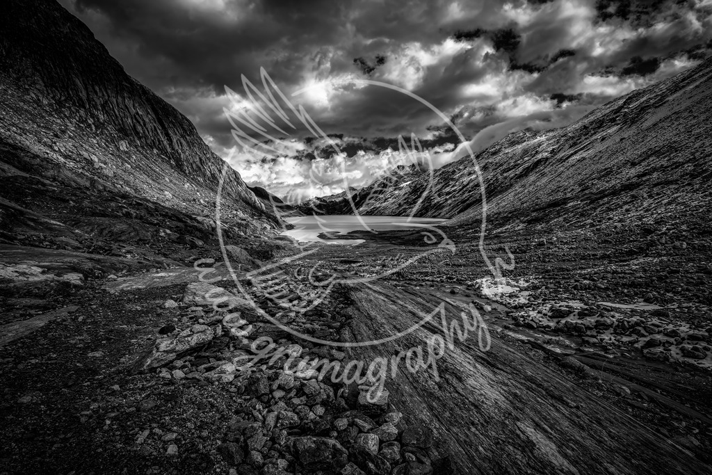 high alpine silence - switzerland_swx | Diese Aufnahme zeigt ein typisches hochalpines Gletschertal der Zentralschweiz: karge Felsflanken, frisches Moränenmaterial, ein milchig-türkisfarbener Gletschersee und ein offenes Wolkenbild. Die kühlen Farbtöne und die klare Struktur des Gesteins vermitteln eindrücklich die Härte und Schönheit dieser Bergwelt.