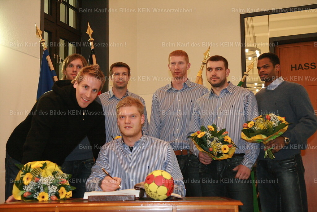 SCM_FotoVideoDesign_09 | Plötzlich mittendrin---2007 gewann der SC Magdeburg den EHF-Pokal. Im Anschluss trug sich die Mannschaft im Alten Rathaus in das Goldene Buch der Landeshauptstadt ein – ein besonderer Moment für den Verein und seine Fans.---Zu meiner eigenen Überraschung stand ich plötzlich mitten im Geschehen und fotografierte die Mannschaft aus nächster Nähe. Bis heute kann ich gar nicht mehr genau sagen, wie ich damals in diesen VIP-Bereich gelangt bin. Wahrscheinlich gehörten einfach eine Portion Mut, Neugier und der richtige Moment dazu.---Damals sagte ich mir oft: „Wenn sich eine Tür öffnet, geh einfach hindurch.“ Genau diese Einstellung hat mich in meinen ersten Berufsjahren immer wieder an Orte geführt, die ich eigentlich nie für erreichbar gehalten hätte.---Wenn ich dieses Foto heute sehe, muss ich schmunzeln. Es erinnert mich daran, dass man Chancen manchmal nicht lange hinterfragen sollte. Man sollte sie einfach nutzen – genau wie an diesem Tag im Magdeburger Rathaus. - Realisiert mit Pictrs.com