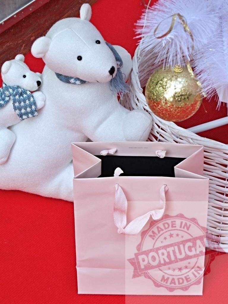 Christmas shopping bag with polar bears and golden ball | Pink shopping bag with polar bears and golden christmas ball decorations lying on red background - Realized with Pictrs.com