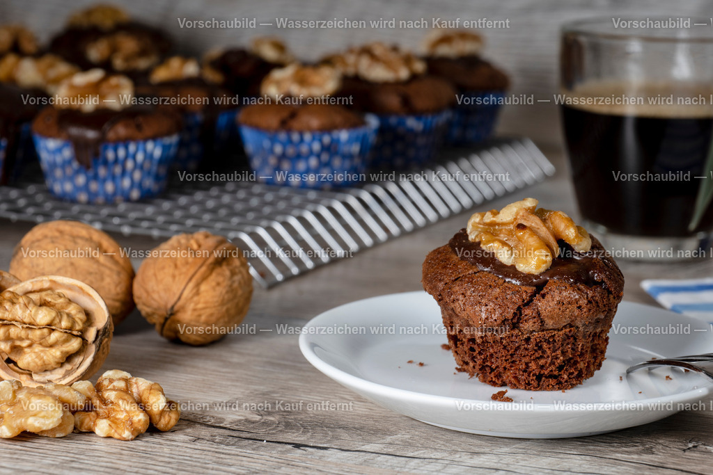 frisch gebackene Wallnussmuffins mit einer Tasse Kaffee | mehrere frisch gebackene Wallnussmuffins auf einen Kuchengitter dekoriert mit Wallnüssen mit und ohne Schalen und einer Tasse Kaffee. - Realisiert mit Pictrs.com