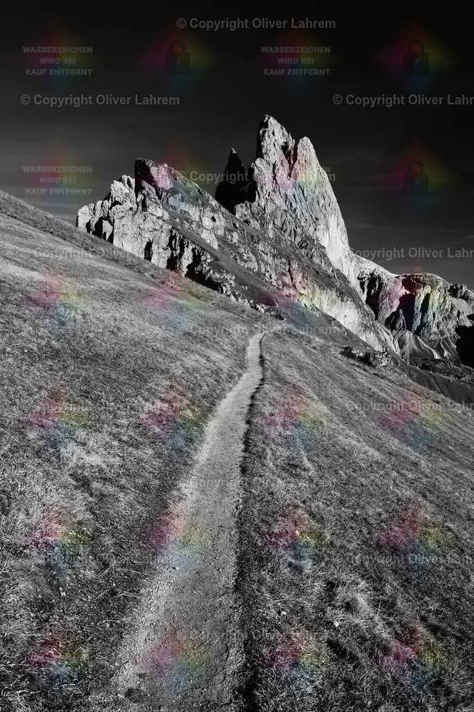 Wanderweg zu den Geisler Spitzen | Ein Wanderweg läuft an einer steilen Bergwiese entlang , direkt auf die Geisler Spitzen zu , die unter dem blauem Himmel stehen.