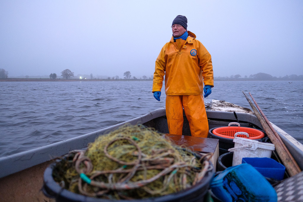 zeitenwende-farbe-03-14 | Matthias Nanz aus Schleswig ist einer der letzten Berufsfischer an der Schlei. Mit seinem Boot fährt er vom Liegeplatz in Missunde zu den Fanggründen in der Schlei. Der Herbst ist die Zeit, in der wie hier an einem kalten Tag Mitte November Raubfische, Heringe und Flundern (Struvbutt) gefangen werden. - Realisiert mit Pictrs.com