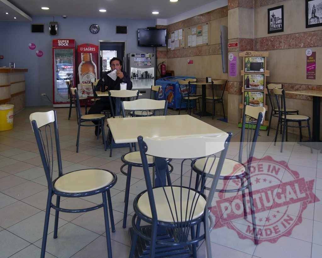 Cafe interior with man enjoying snack and beverage | Interior of a cafe with a lone man sitting at a table eating while surrounded by empty tables - Realized with Pictrs.com
