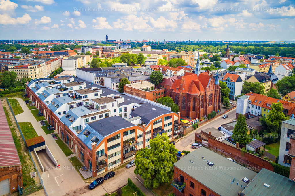 Magdeburg Buckau Quartier Kirche St Norbert Karl-Schmidt-Straße-0012 | Diese Luftaufnahme zeigt das eindrucksvoll sanierte Buckauquartier, in dem eine ehemalige Sporthalle zu modernen Wohnungen umgebaut wurde. Das Bauwerk steht beispielhaft für den gelungenen Wandel historischer Gebäude und zeigt, wie bestehende Architektur durch kreative Umnutzung ein neues Leben erhalten kann. Direkt daneben erhebt sich die Kirche St. Norbert und bildet mit ihrer markanten Architektur einen reizvollen Kontrast zur modernen Wohnbebauung. Gemeinsam prägen beide Gebäude das unverwechselbare Stadtbild des beliebten Magdeburger Stadtteils Buckau.Dieses Motiv verdeutlicht die große Vielfalt der Architektur-Highlights, aus denen Ihr individueller Luftbildkalender zusammengestellt werden kann. Ob denkmalgeschützte Bauwerke, sanierte Industriegebäude, moderne Wohnquartiere oder markante Kirchen – Sie entscheiden selbst, welche Architektur Ihren Kalender repräsentieren soll. Die gezeigten Aufnahmen sind Beispiele und können jederzeit durch andere Motive aus dem umfangreichen Luftbildarchiv ersetzt oder ergänzt werden.So entsteht ein hochwertiger Firmenkalender mit persönlichem Charakter und regionalem Bezug. Sie wählen Ihre Wunschmotive aus, ich übernehme die professionelle Gestaltung und Umsetzung. Die individuelle Motivauswahl gehört selbstverständlich zum Service und ermöglicht einen Kalender, der die architektonische Vielfalt Magdeburgs genau nach Ihren Vorstellungen präsentiert. - Realisiert mit Pictrs.com