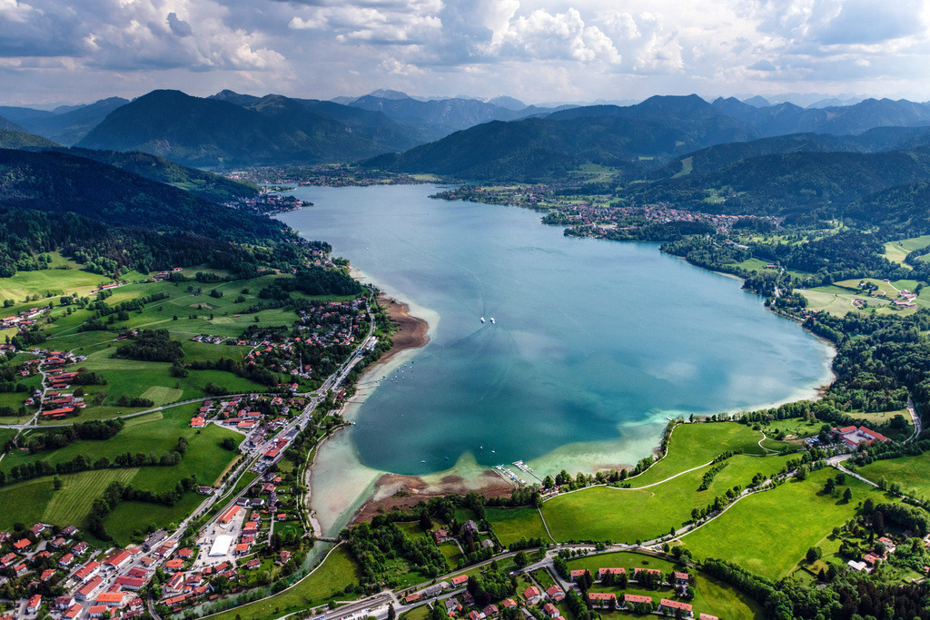 dr__0097993.jpg | BAD WIESSEE 19.05.2022 Der Tegernsee in den Bayerischen Alpen im Bundesland Bayern zählt zu den saubersten Seen Deutschlands und ist ein beliebtes Ausflugs- und Fremdenverkehrsziel. Es ist außerdem wichtig für die Trinkwasserversorgung und als Hochwasserrückhaltebecken. Aufnahme bei bewölktem Himmel mit Schattenwurf der Wolken auf der Seefläche. // Riparian areas on the lake area of Tegernsee in Bad Wiessee in the state Bavaria, Germany. Foto: Daniel Reiter