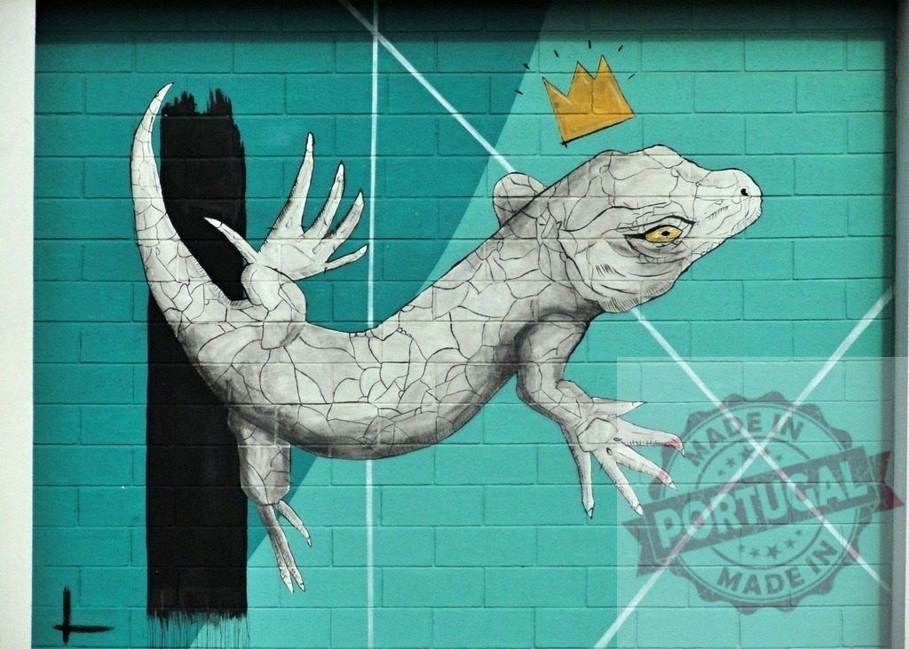 Crowned lizard king mural on teal brick wall | Gray lizard wearing a golden crown painted as street art on a vibrant teal wall - Realisiert mit Pictrs.com