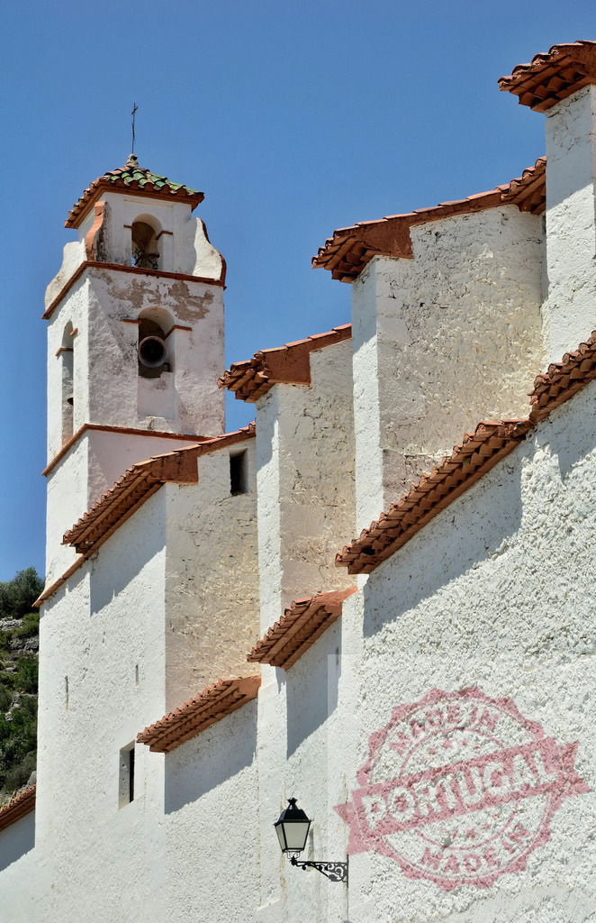 White church bell tower against blue sky. Spain - Castellon | White church bell tower and facade with terra cotta roof tiles against a clear blue sky - Realisiert mit Pictrs.com