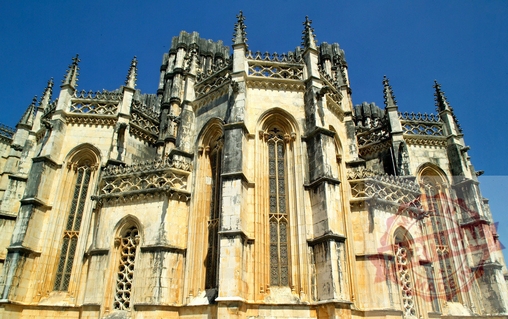 Batalha Monastery, Portugal, gothic architecture facade details | Batalha Monastery showcasing intricate gothic architecture details against a clear blue sky - Realisiert mit Pictrs.com