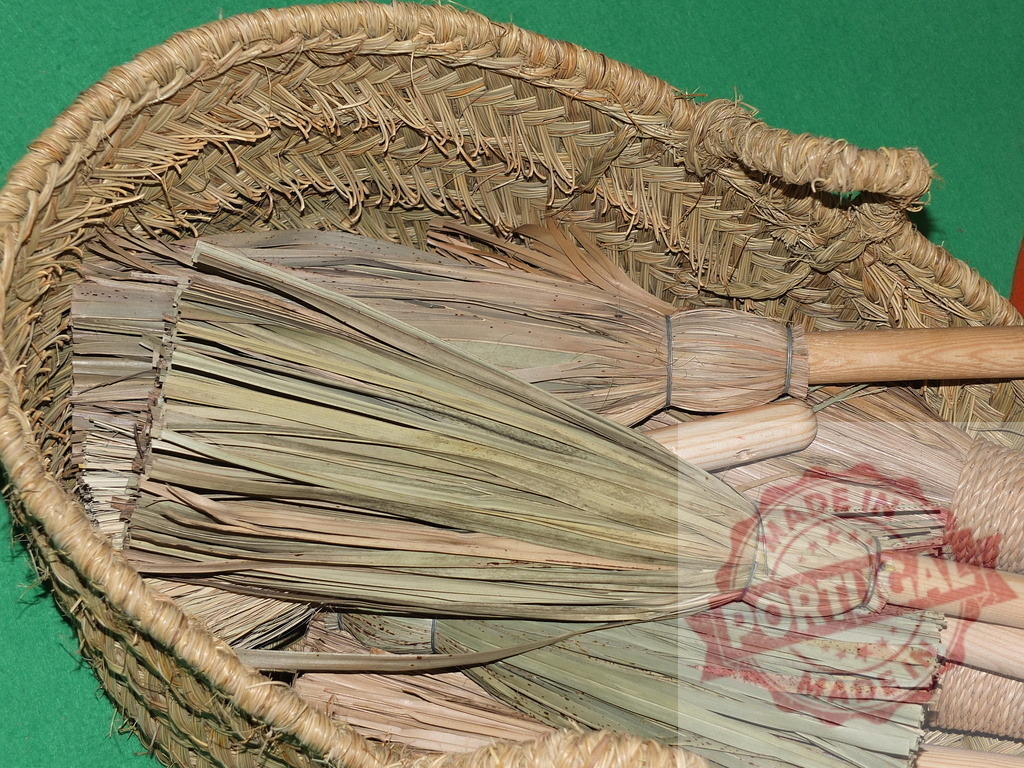 Handmade brooms made from natural palm leaves in woven basket | Many traditional brooms made from palm leaves with wooden handles, packed in a large woven basket - Realized with Pictrs.com