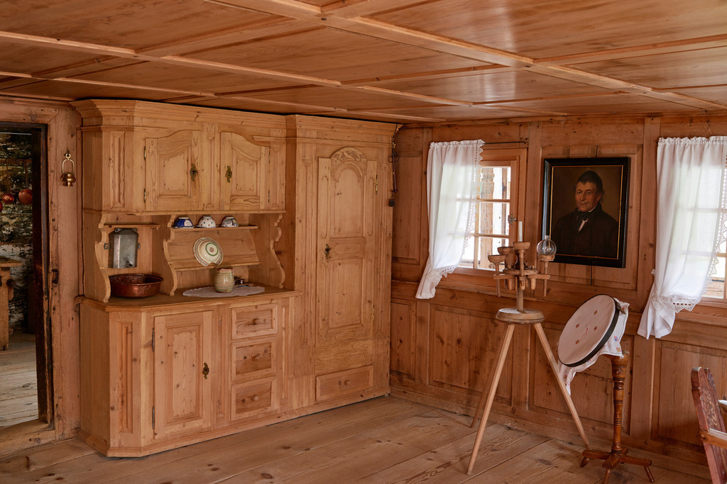 Heimatmuseum Bezau | Bezau, Austria - July 27, 2017: Heimatmuseum Bezau, Blick in das Wohnzimmer mit Holzschrank, Stickarbeit und einem Kerzenhalter mit Schusterkugel. - Realisiert mit Pictrs.com