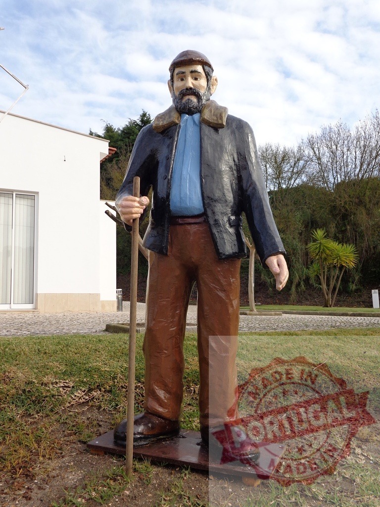 Imposing wooden statue of farmer holding walking stick in rural landscape | Large weathered statue of bearded farmer holding wooden staff, adding rustic charm to outdoor setting - Realisiert mit Pictrs.com